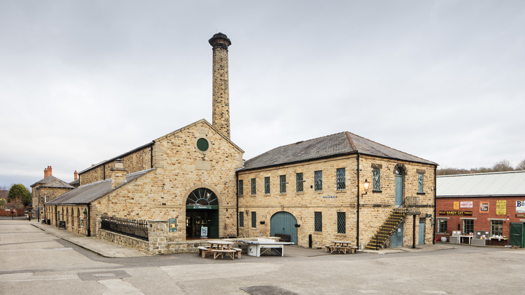 Elsecar Heritage Centre building made of stone with green windows and doors and a tall chimney