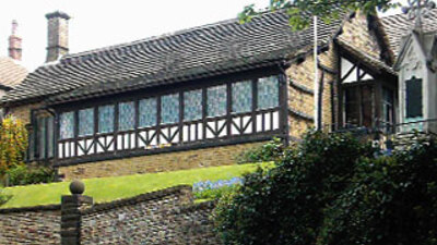 The museum building is on top of a slight incline, it has a thatched roof and white and black strips on the front of the building