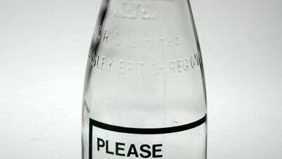 an empty milk bottle which says please rinse and return on the front