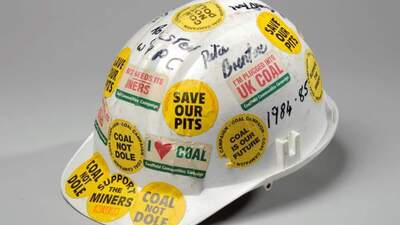 A white helmet covered in stickers with slogans such as coal not dole and save our pits