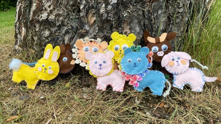 Felt animals such as lions, rabbits and cows at the base of a tree