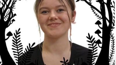 A person with long brown hair, wearing a black shirt, smiles at the camera. Decorative black foliage silhouettes frame the image. The name "Kira Powell" is written in purple and white text at the bottom.