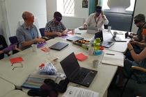 A group of people sitting around the a table wearing blindfolds, taking part in an access training activity.