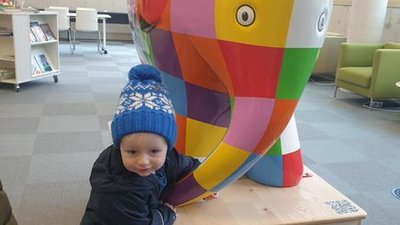 Child next to a multi coloured elephant statue