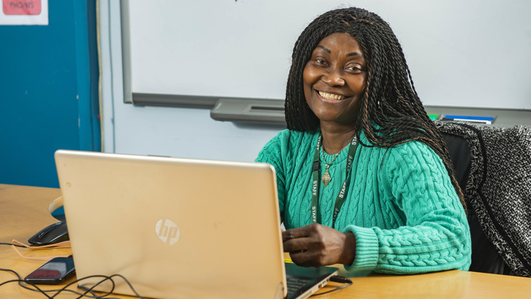 Woman smiling and sitting at a computer 