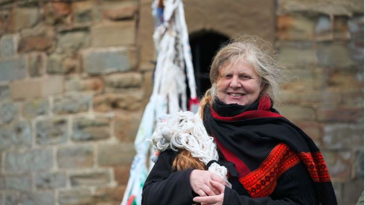 Photograph of Rachel Chapman smiling at the camera wearing a black and red scarf