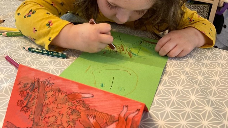 Little girl drawing on green paper