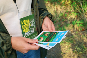 Person holding illustrated postcards and wearing a 'A Walk Around Town' Penistone pack