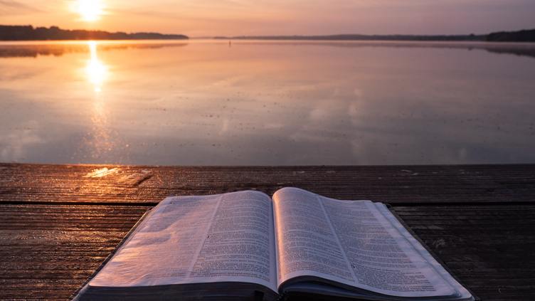 Open book on a bench overlooking a sunset