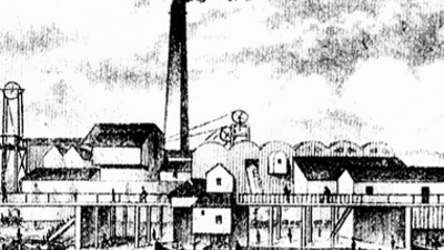 Black and white drawing of an old industrial factory with a tall smokestack emitting smoke, several buildings, and a canal with a barge in front.